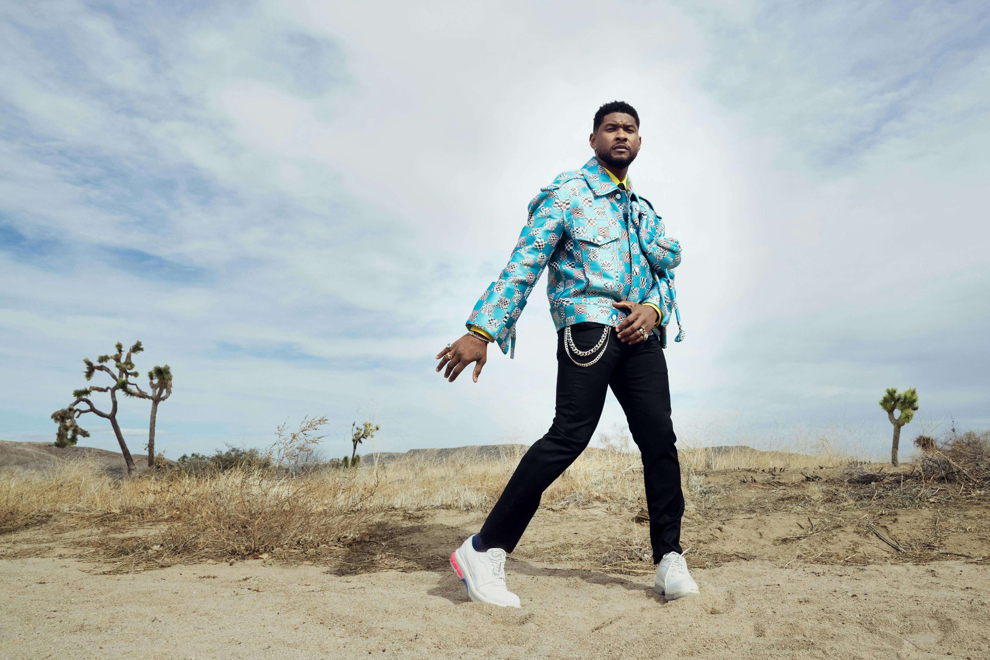 Usher indossa giacca di seta motivo Damier Distorted, camicia e pantaloni, cravatta di seta e scarpe "LV Fusion Derby", LOUIS VUITTON; orecchini e anelli con diamanti, JACQUIE AICHE; ear cuff, REPOSSI; anello, HOORSENBUHS; bracciale e anello, Usher's own. 