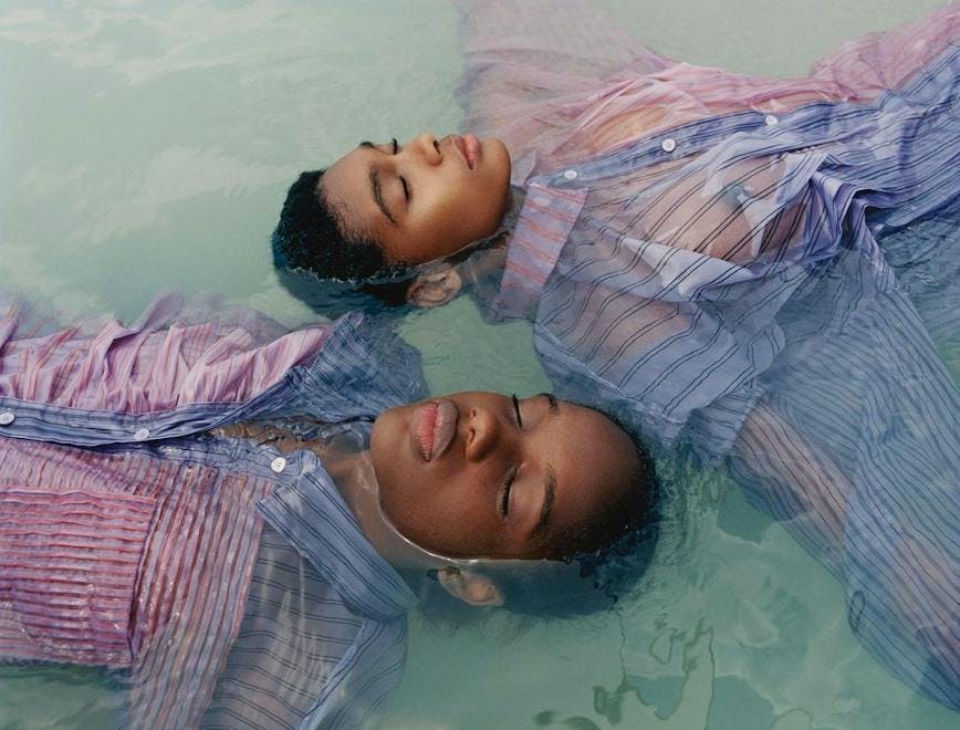 Due ragazzi di colore galleggiano in acqua vestiti 